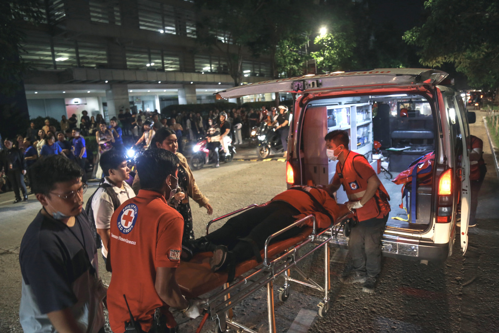 Medical workers load a resident into an ambulance as others stay outside buildings after a strong earthquake struck Cebu city, central Philippines, on Tuesday, Sept. 30, 2025. (AP Photo/Jacqueline Hernandez)