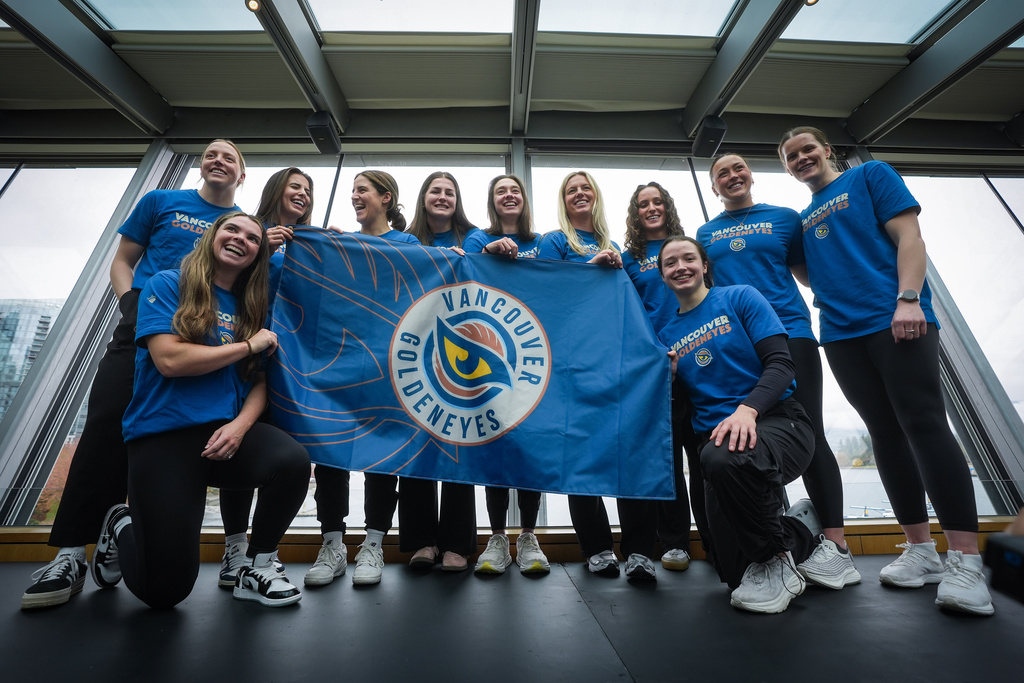 Vancouver Goldeneyes players pose with their new logo and team name following an unveiling at a PWHL hockey news conference, Thursday, Nov. 6, 2025, in Vancouver, British Columbia. (Darryl Dyck/The Canadian Press via AP)