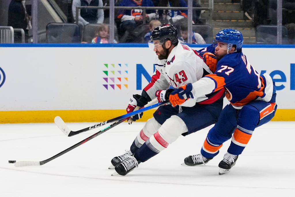 New York Islanders' Tony Deangelo (77) defends Washington Capitals' Tom Wilson (43) during the third period of an NHL hockey game Saturday, Oct. 11, 2025, in Elmont, N.Y. (AP Photo/Frank Franklin II)