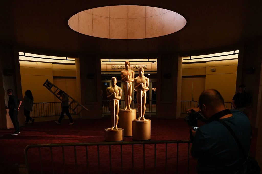 People look on as workers install Oscar statues Saturday, March 14, 2026, at the Dolby Theatre in Los Angeles, in preparation for Sunday's 98th Academy Awards ceremony. (AP Photo/Gregory Bull)