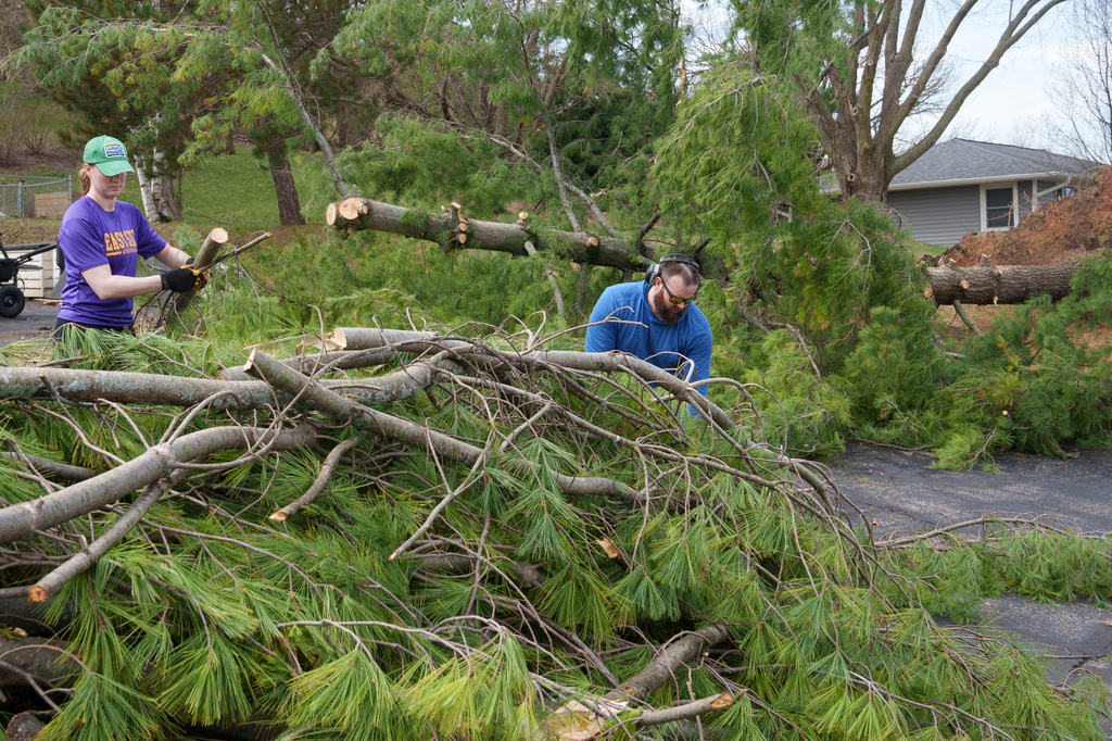 Bethany and Cody Spooner remove tree branches from a pine that came down during severe overnight storms, Tuesday, April 14, 2026, in Deforest, Wis. (AP Photo/Jon Elswick)