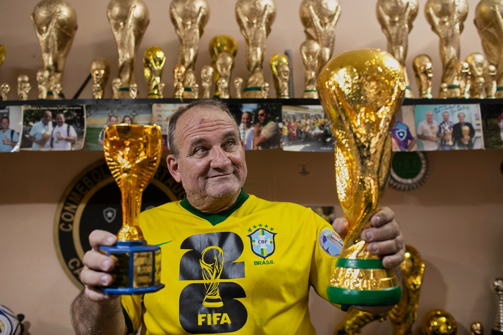 Jarbas Meneghini Carlini poses for a photo holding FIFA World Cup trophy replicas he made, at his home in Rio de Janeiro, Friday, May 15, 2026. (AP Photo/Bruna Prado)