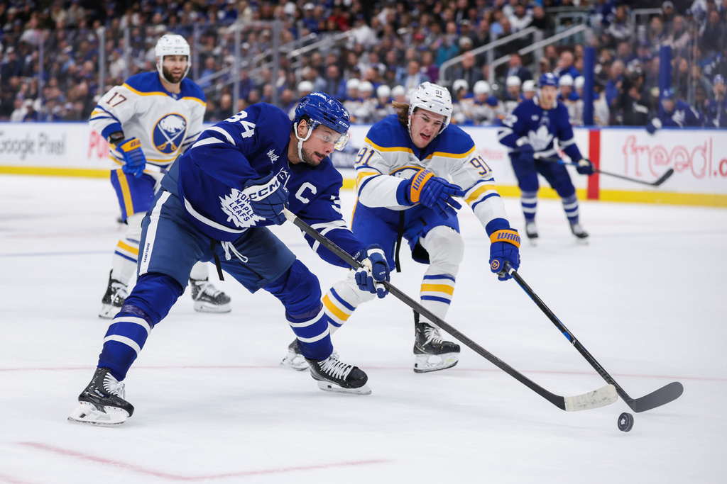Toronto Maple Leafs' Auston Matthews battles for the puck with Buffalo Sabres' Josh Doan (91) during the second period of an NHL hockey game in Toronto, Saturday, Oct. 25, 2025. (Nick Iwanyshyn/The Canadian Press via AP)