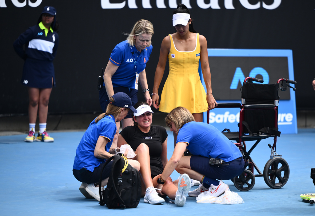 Priscilla Hon, top right, of Australia looks on as her opponent Marina Stakusic of Canada receives medical attention during their first round match at the Australian Open tennis tournament in Melbourne, Australia, Monday, Jan. 19, 2026. (Joel Carrett/AAP Image via AP)