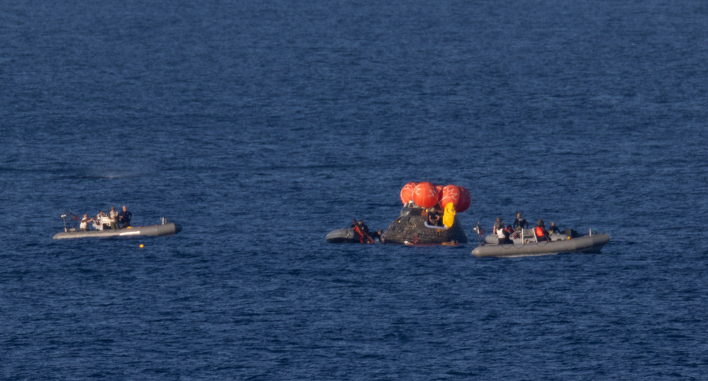 In this photo provided by NASA, recovery teams work to secure the Orion spacecraft carrying Artemis II crewmembers after splashdown in the Pacific Ocean off the coast of California, Friday, April 10, 2026. (Joel Kowsky/NASA via AP)