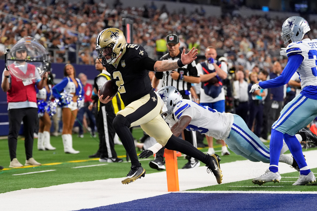 New Orleans Saints quarterback Spencer Rattler (2) scores a touchdown in front of Dallas Cowboys linebacker Isaiah Land (58) during the first half of a preseason NFL football game, in Arlington, Texas, Friday, Aug. 28, 2026. (AP Photo/Tony Gutierrez)