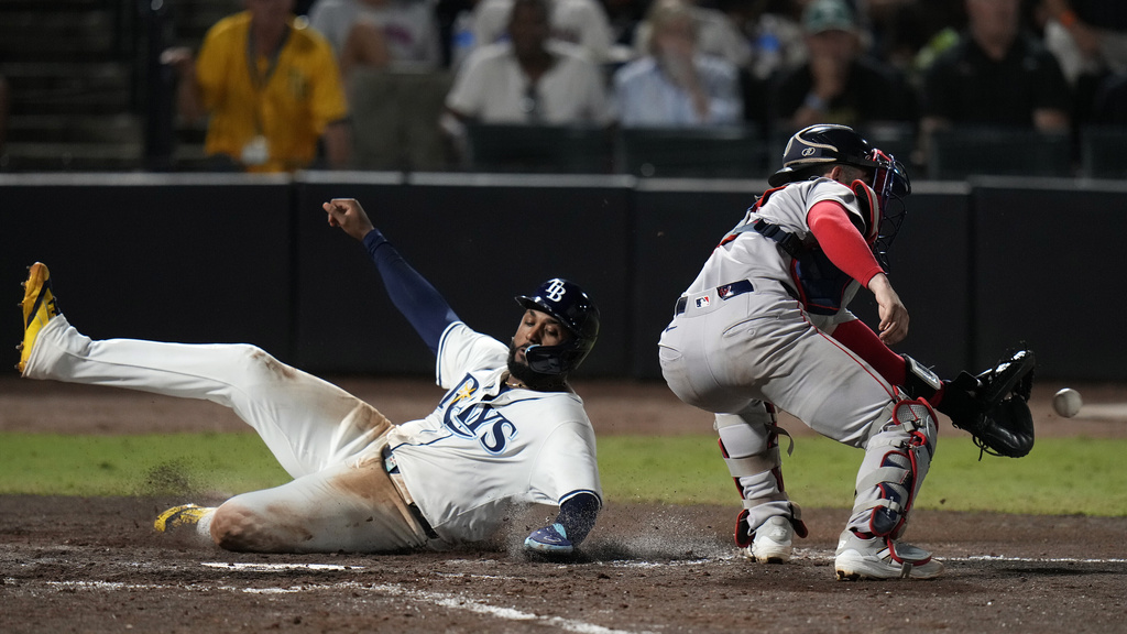 Tampa Bay Rays' Junior Caminero scores past Boston Red Sox catcher Connor Wong, right, on a two-run single by Christopher Morel during the eighth inning of a baseball game Sunday, Sept. 21, 2025, in Tampa, Fla. (AP Photo/Chris O'Meara)