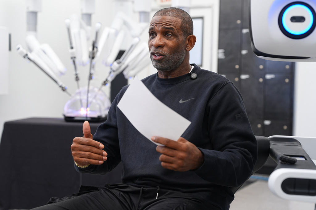 Colorado head football coach Deion Sanders talks after working the Da Vinci robotic surgical machine used to remove his cancerous bladder last year during a demonstration of the device Tuesday, June 23, 2026, in Boulder, Colo. (AP Photo/David Zalubowski)