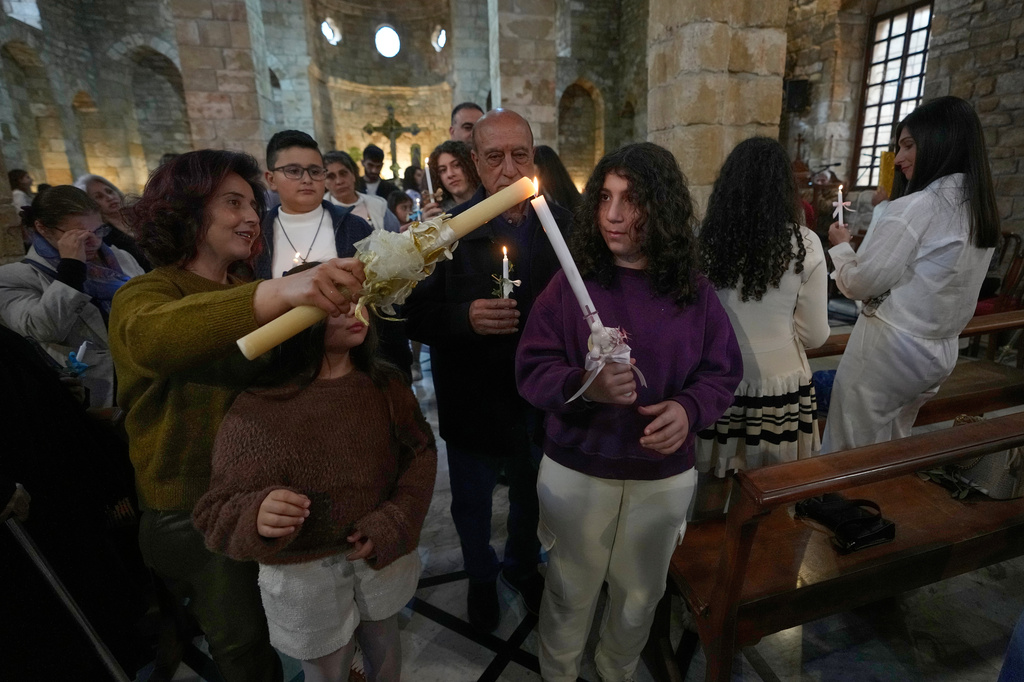 Worshipers light candles as they attend Palm Sunday Mass procession at Saint Thomas Cathedral, in the southern port city of Tyre, south Lebanon, Sunday, March 29, 2026. (AP Photo/Hussein Malla)