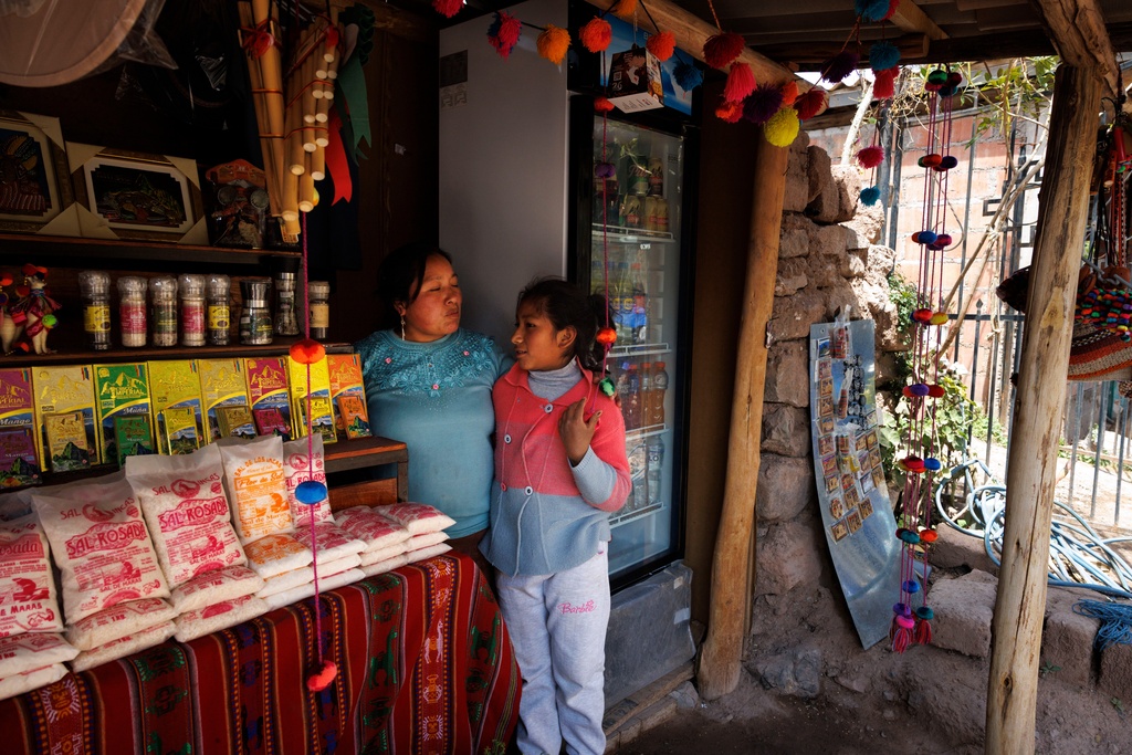 Ilda, shop owner, left, hugs her daughter, Gabbi, at the shop in Pichingoto, a village outside of Salineras de Maras, Maras salt mines, in the Sacred Valley of Peru, on Sunday, Aug. 31, 2025. "The shops have to be run by residents of these towns," Ilda said. (AP Photo/Alie Skowronski)