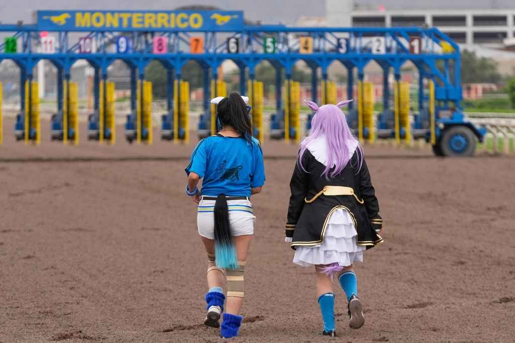 FILE - Women dressed as race horses inspired by the Japanese franchise Umamusume: Pretty Derby, walk before competing at the Monterrico racecourse in Lima, Peru, Feb. 27, 2026. (AP Photo/Martin Mejia, File)