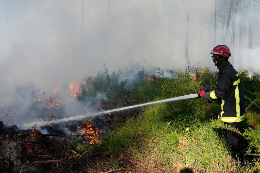 A firefighter works to suppress flames near Lacanau, as wildfires rage outside Bordeaux, France, Monday, July 27, 2026. (AP Photo/Baz Ratner)