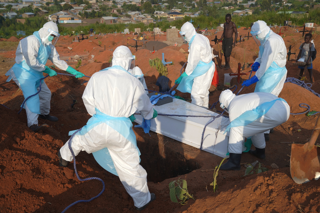 People in protective gear lower into a grave the coffin containing the remains of Jacques Lobo Dhena, who died of Ebola, during a burial service in Bunia, Ituri province, eastern Congo, Wednesday, Aug. 12, 2026. (AP Photo/Dieudonne Dirole)