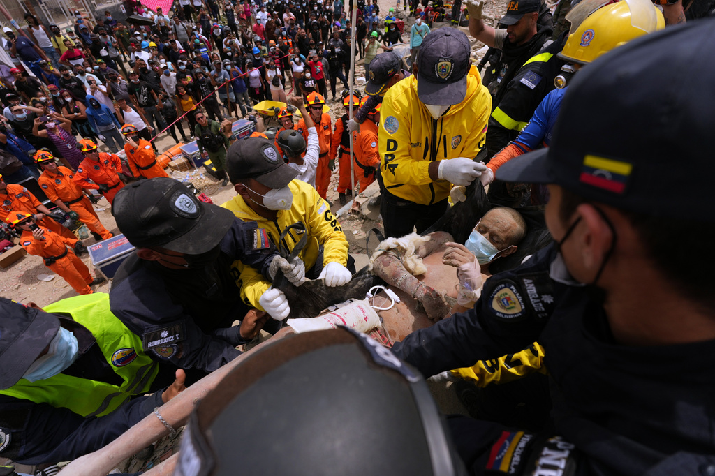 Rescue workers carry a man rescued from the rubble of a building that collapsed in the earthquakes that struck La Guaira, Venezuela, Sunday, June 28, 2026. (AP Photo/Matias Delacroix)