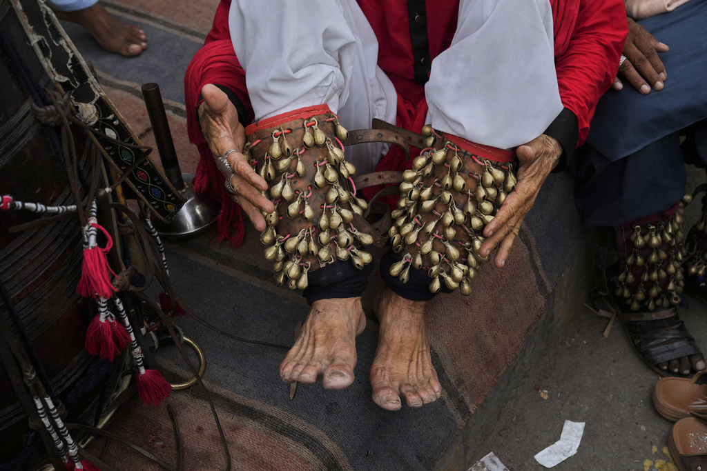A spiritual path devotee locally called 'Malang' ties 'Ghungroo', a set of small metallic bells strung together, on his feet for performing a devotional dance called 'Dhamaal' during celebrations of the three-day annual festival or 'Urs' of mystic and scholar Hazrat Ali Hajveri, popularly known as Data Ganj Bakhsh at his shrine, in Lahore, Pakistan, Wednesday, Aug. 13, 2025. (AP Photo/K.M. Chaudary)