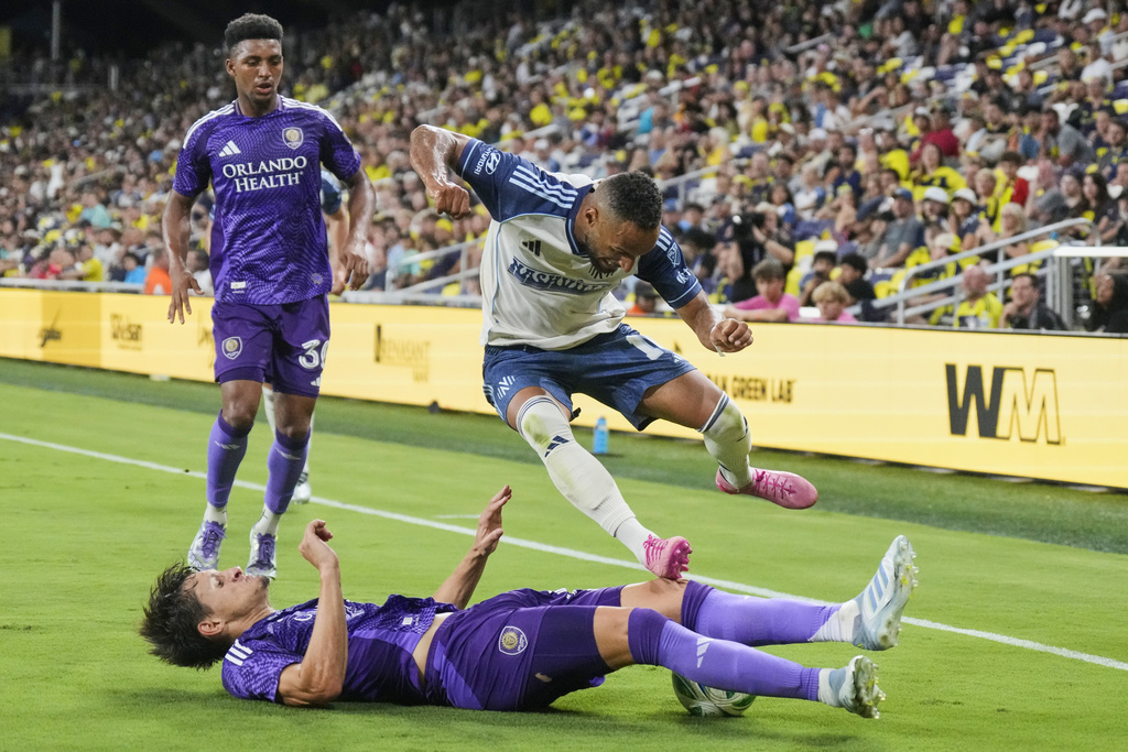 Orlando City defender Rodrigo Schlegel, slides underneath Nashville SC midfielder Hany Mukhtar, above as during the second half of an MLS soccer match Saturday, Aug. 23, 2025, in Nashville, Tenn. (AP Photo/George Walker IV)