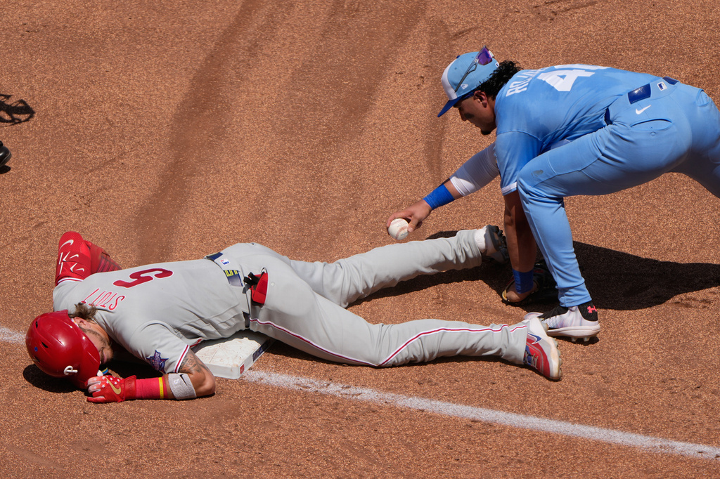 Philadelphia Phillies' Bryson Stott (5) beats the tag at third by Kansas City Royals third baseman Josh Rojas after hitting a triple during the fifth inning of a baseball game Sunday, July 5, 2026, in Kansas City, Mo. (AP Photo/Charlie Riedel)