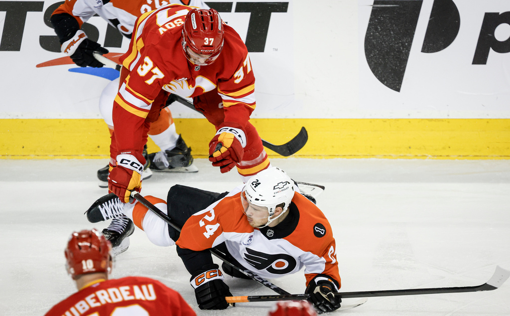 Philadelphia Flyers' Nick Seeler, right, is checked by Calgary Flames' Yan Kuznetsov during second period NHL hockey action in Calgary on Wednesday, Dec. 31, 2025. (Jeff McIntosh/The Canadian Press via AP)