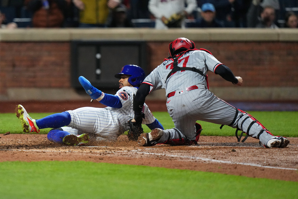 New York Mets' Francisco Lindor, left, slides past Minnesota Twins catcher Victor Caratini to score on a double by Francisco Alvarez during the fourth inning of a baseball game Wednesday, April 22, 2026, in New York. (AP Photo/Frank Franklin II)