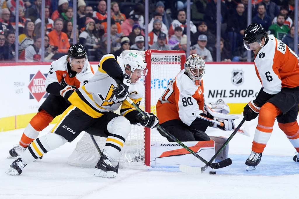 Pittsburgh Penguins' Sidney Crosby, center, tries to get a shot past Philadelphia Flyers' Travis Sanheim, from right, Dan Vladar and Christian Dvorak during the first period of an NHL hockey game Monday, Dec. 1, 2025, in Philadelphia. (AP Photo/Matt Slocum)