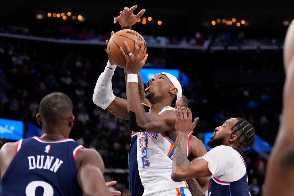 Oklahoma City Thunder guard Shai Gilgeous-Alexander, center, shoots as Los Angeles Clippers guard Kris Dunn, left, and forward Derrick Jones Jr., right, defend during the first half of an NBA basketball game Wednesday, April 8, 2026, in Inglewood, Calif. (AP Photo/Mark J. Terrill)