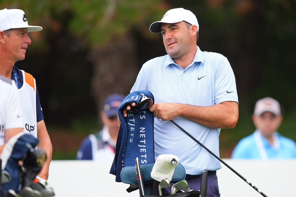 Scottie Scheffler, right, prepares for a tee shot on the 14th hole during the first round of the Byron Nelson golf tournament in McKinney, Texas, Thursday, May 21, 2026. (AP Photo/LM Otero)