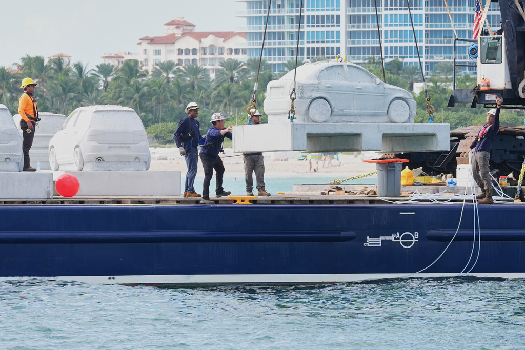 Workers prepare to submerge a marine grade concrete car that will be attached with native corals as part of a pioneering underwater marine sculpture park Tuesday, Oct. 28, 2025, in Miami Beach, Fla. (AP Photo/Marta Lavandier)