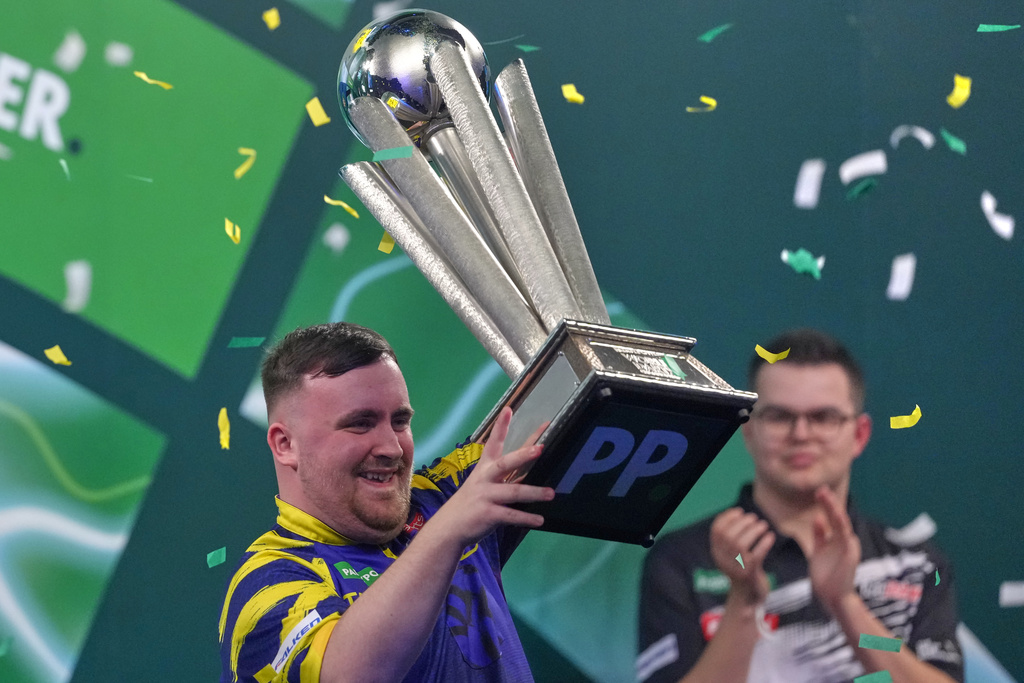 England's Luke Littler lifts the trophy after winning the World Darts Championships final match against Gian van Veen of the Netherlands at Alexandra Palace in London, Saturday, Jan. 3, 2026.(AP Photo/Dave Shopland)