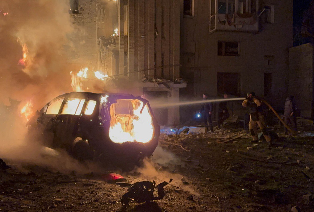 In this photo provided by the Ukrainian Emergency Services on Monday, Dec. 8, 2025, a rescue worker puts out a fire of a car in front of a residential building damaged by a Russian strike in Sumy region, Ukraine. (Ukrainian Emergency Service via AP)