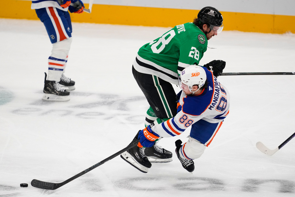 Edmonton Oilers' Andrew Mangiapane (88) takes a hit from Dallas Stars' Alexander Petrovic (28) in the third period of an NHL hockey game Tuesday, Nov. 4, 2025, in Dallas. (AP Photo/Tony Gutierrez)