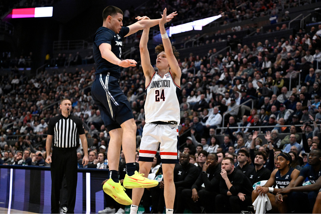 UConn guard Braylon Mullins (24) follows through on a three-point basket as Xavier guard All Wright (3) defends in the first half of an NCAA college basketball game, Tuesday, Feb. 3, 2026, in Hartford, Conn. (AP Photo/Jessica Hill)
