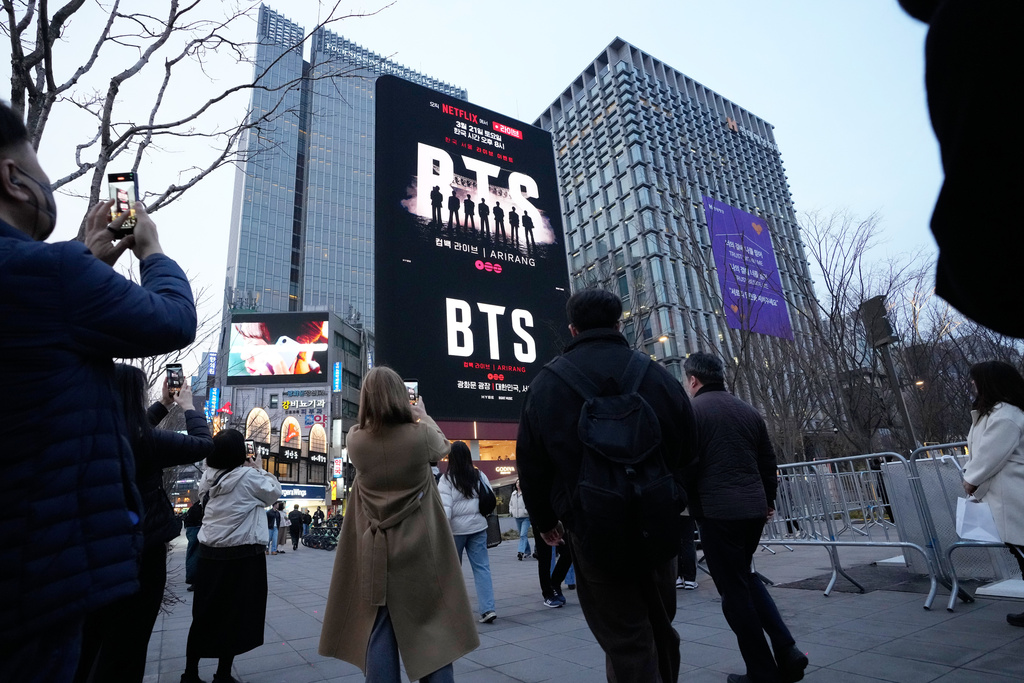 People take photos of a screen promoting a comeback concert of K-pop group BTS at Gwanghwamun Square in Seoul, Wednesday, March 18, 2026. (AP Photo/Ahn Young-joon)