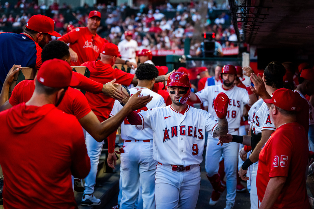 Los Angeles Angels shortstop Zach Neto (9) is greeted by teammates after scoring during the 3rd inning of a baseball game against the Texas Rangers, Tuesday, Aug. 11, 2026, in Anaheim, Calif. (AP Photo/Ethan Swope)