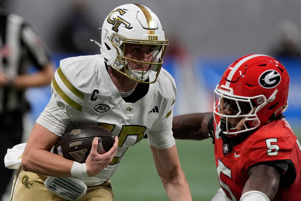 Georgia Tech quarterback Haynes King (10) runs against Georgia linebacker Raylen Wilson (5) during the first half of an NCAA college football game, Friday, Nov. 28, 2025, in Atlanta. (AP Photo/Mike Stewart)