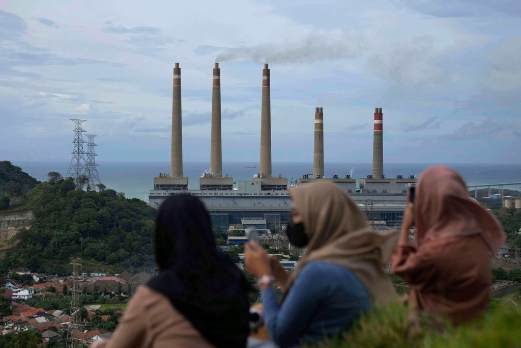 FILE - Women sit on a hill overlooking the Suralaya coal power plant in Cilegon, Indonesia, Jan. 8, 2023. (AP Photo/Dita Alangkara, File)