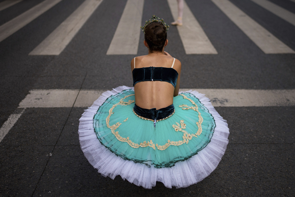 Irina, 11, of the Romanian National Opera's Ballet Studio, takes pictures of her colleagues after dancing outside the National History Museum of Romania during Dance Night, an event featuring a wide variety of dance styles performed on the Calea Victoriei avenue in Bucharest, Romania, Saturday, Aug. 23, 2025. (AP Photo/Andreea Alexandru)