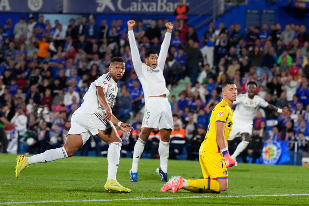 Real Madrid's Kylian Mbappe, left, looks at the ball after scoring during a La Liga soccer match between Getafe and Real Madrid in Getafe, Spain, Sunday, Oct. 19, 2025. (AP Photo/Manu Fernandez)