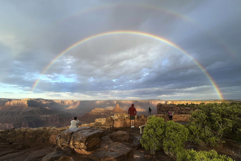 People gather at an overlook as a double rainbow appears over Dead Horse Point State Park, near Moab, Utah, after sunrise and a thunderstorm moved through, Thursday, Oct. 9, 2025. (AP Photo/Becky Bohrer)