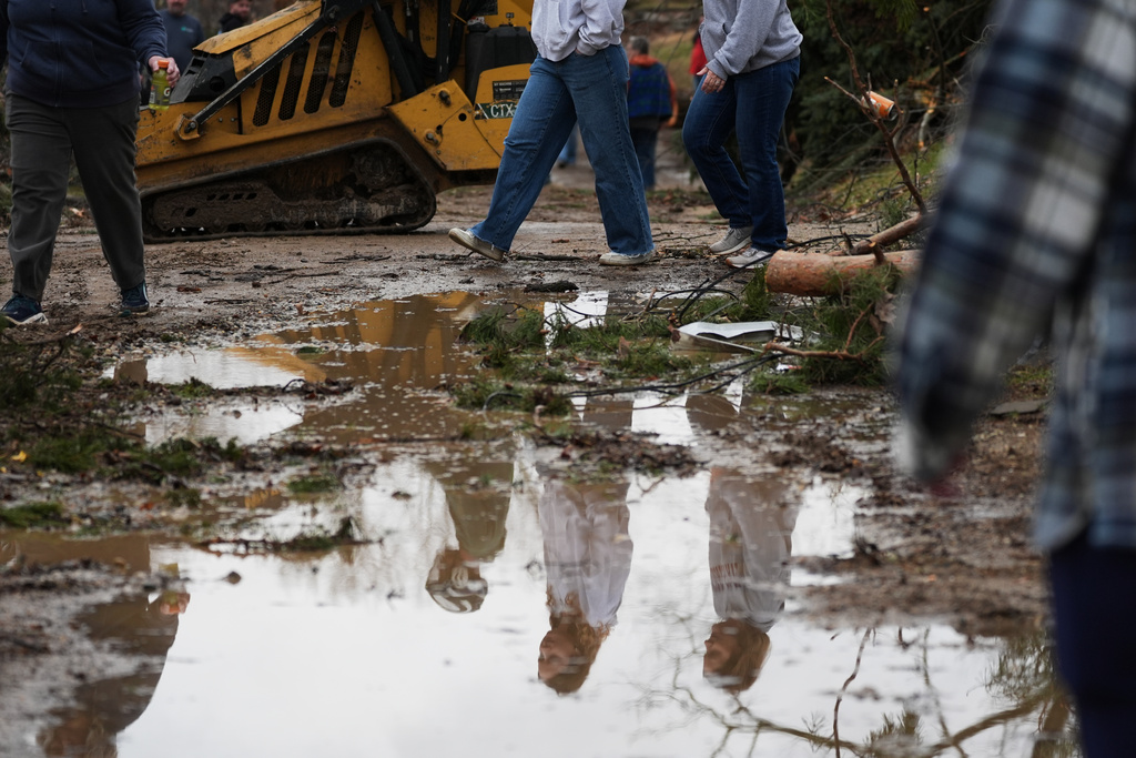 Volunteers are reflected in a puddle of water in the aftermath of a powerful storm that ripped through the area a day earlier, in Union City Mich., Saturday, March 7, 2026. (AP Photo/Nam Y. Huh)