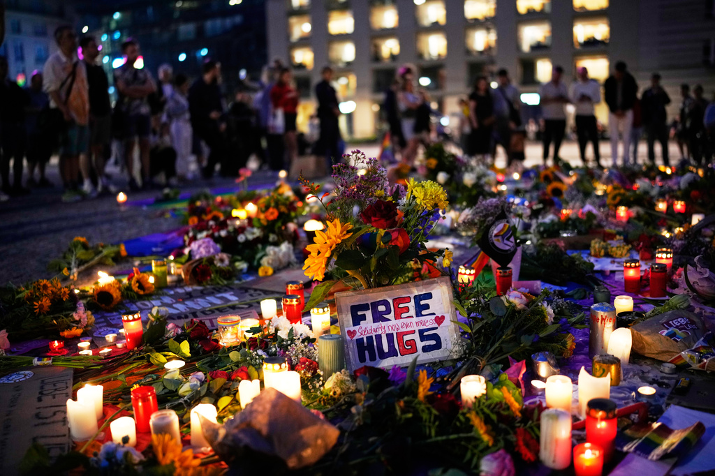 People gather in front of the Brandenburg Gate illuminated with the message "Berlin, city of freedom", commemorating the victims, after a car rammed into a crowd at the Pride March in Berlin, Sunday, July 26, 2026. (AP Photo/Ebrahim Noroozi)