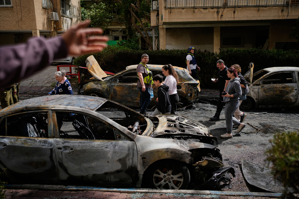 Residents and Israeli security forces inspect a site struck by an Iranian missile in Petah Tikva, Israel, Tuesday, March 31, 2026. (AP Photo/Ohad Zwigenberg)