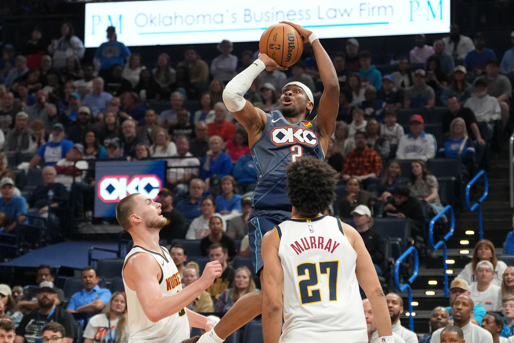 Oklahoma City Thunder guard Shai Gilgeous-Alexander, top, shoots over Denver Nuggets guard Christian Braun, left, and guard Jamal Murray (27) during the second half of an NBA basketball game, Friday, Feb. 27, 2026, in Oklahoma City. (AP Photo/Kyle Phillips)