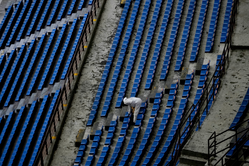 FILE - A worker cleans the seats at San Siro Stadium, where the opening ceremony for the Milan Cortina 2026 Winter Olympics will take place, in Milan, Italy, on Jan. 27, 2025. (AP Photo/Luca Bruno, File)