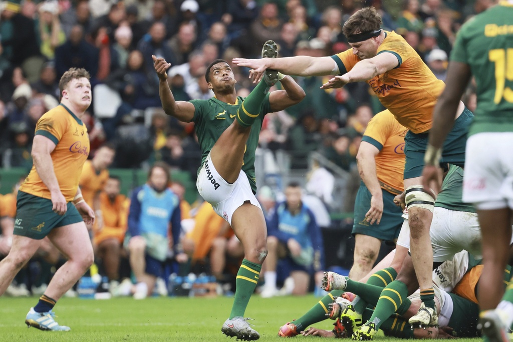 South Africa's Grant Williams, centre, kicks the ball as Australia's Nick Frost charges towards him during a rugby championship test match between South Africa and Australia, at Cape Town stadium in Cape Town, South Africa, Saturday, Aug. 23, 2025. (AP Photo/Halden Krog)