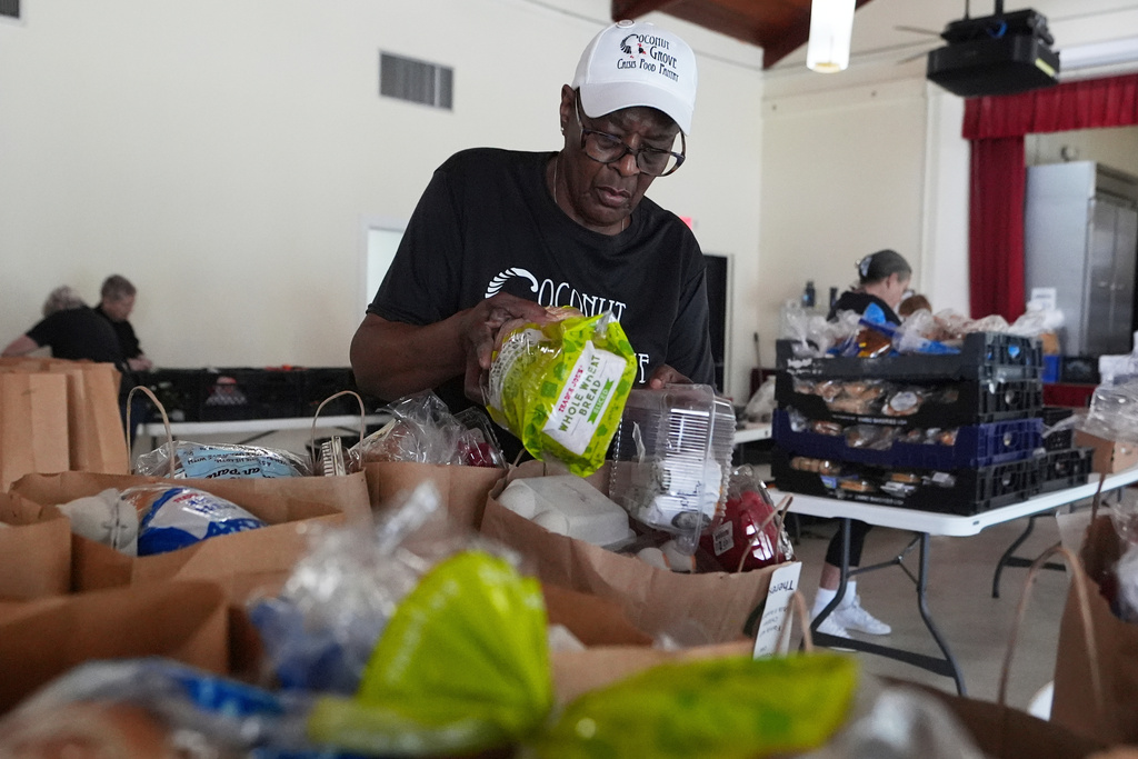 FILE - Volunteer Ollie Taylor fills bags with food at the Coconut Grove Crisis Food Pantry, which offers fresh food and meals free of charge on a weekly basis to residents, Aug. 26, 2025, in the Coconut Grove neighborhood of Miami. (AP Photo/Lynne Sladky, File)