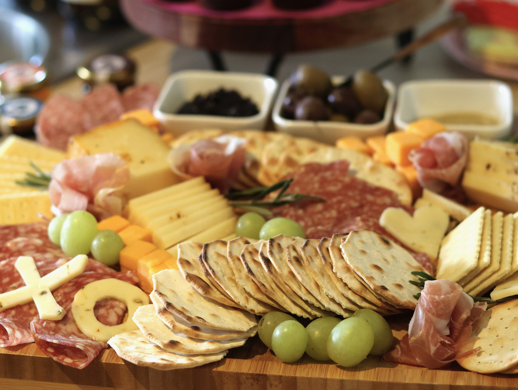 An arrangement of crackers, cheeses, meats, fruits and spreads is prepared for guests at a gathering of friends at an apartment in Flagstaff, Ariz., on Sunday, Feb. 15, 2026. (AP Photo/Cheyanne Mumphrey)