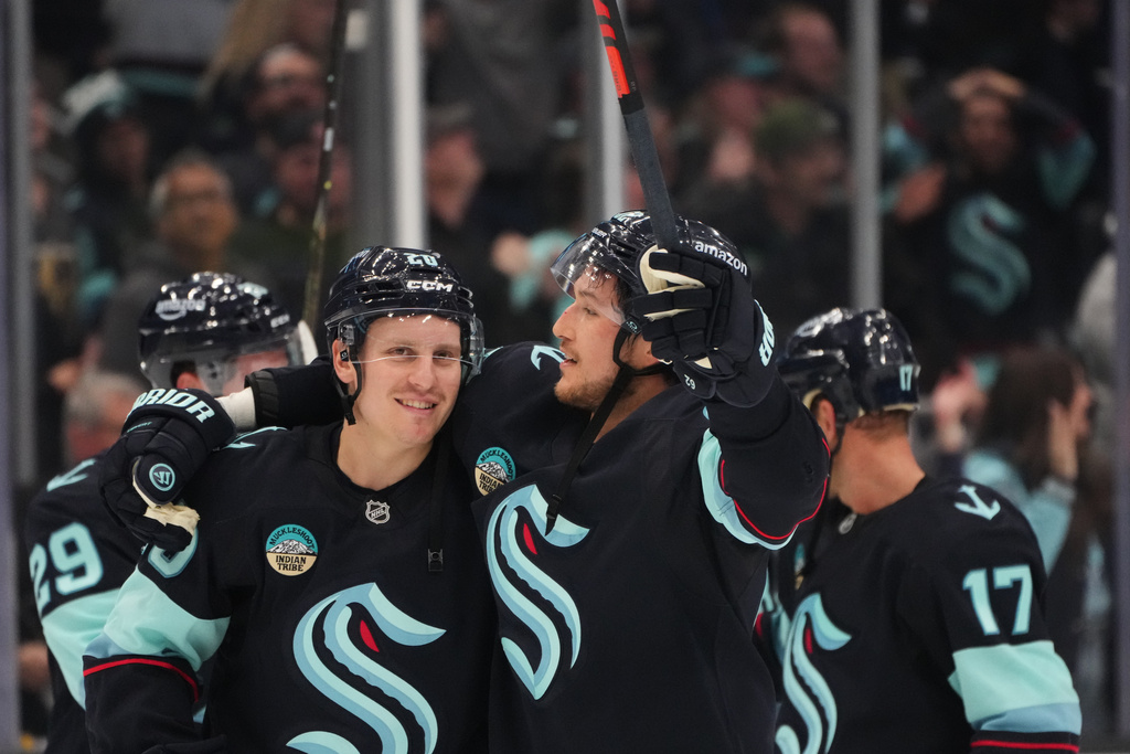 Seattle Kraken right wing Eeli Tolvanen, left, celebrates an overtime win with defenseman Brandon Montour, right, after a game-winning goal in overtime from teammate Jared McCann against the Vegas Golden Knights in an NHL hockey game Saturday, Oct. 11, 2025, in Seattle. (AP Photo/Lindsey Wasson)