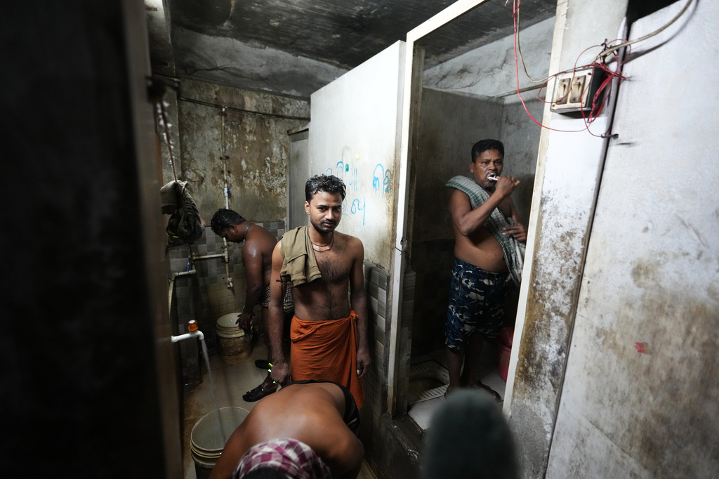 Power loom factory worker Sibaram Pradhan, right, brushes his teeth as others bathe at their residential quarters in Surat, India, Thursday, May 28, 2026. (AP Photo/Ajit Solanki)