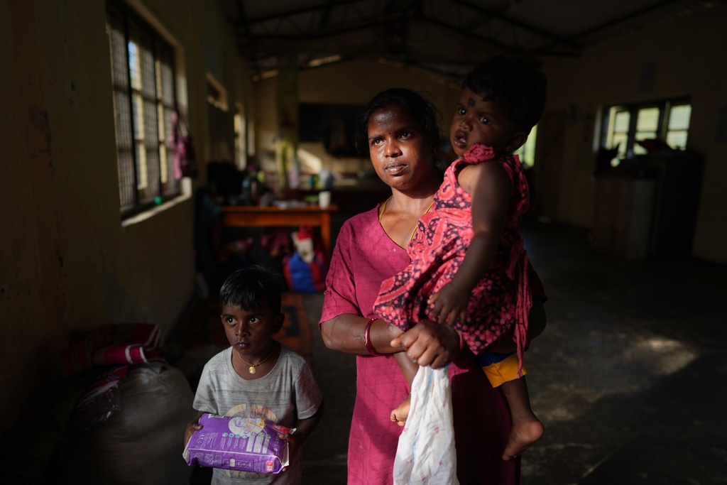Sellamuttu Darshani Devi, a tea plantation worker evacuated after Cyclone Ditwah led to floods and landslides, shelters with her children at a safety center in Galamuduna Estate in Dolosbage, Sri Lanka, Friday, Dec. 12, 2025. (AP Photo/Eranga Jayawardena)
