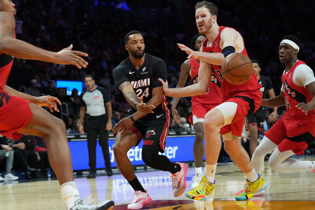 Miami Heat guard Norman Powell (24) passes the ball as Toronto Raptors forward RJ Barrett (9) defends during the first half of an NBA basketball game, Monday, Dec. 15, 2025, in Miami. (AP Photo/Lynne Sladky)